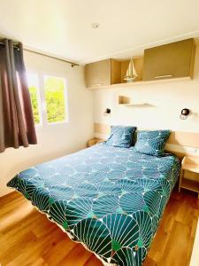 una camera con letto e piumone blu di Évasion océanique : Mobil-home dans un camping 4* à 50m de l'océan a La Bétaudière