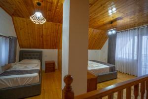 two beds in a room with a wooden ceiling at Vila Alpini Lepushe in Lëpushë