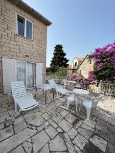 a group of chairs and tables on a patio at Central Studio Apartments & Dormitory Rooms in Supetar