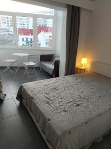 a bedroom with a bed and a couch and a table at Your Home near the beach - Sesimbra in Sesimbra