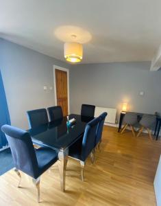 a dining room with a black table and blue chairs at Medway Getaway - 3 Bed Home with Luxury Bathroom in Chatham