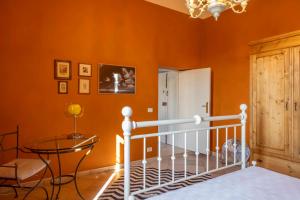 een slaapkamer met een oranje muur met een bed en een tafel bij La Siesta in Poggibonsi