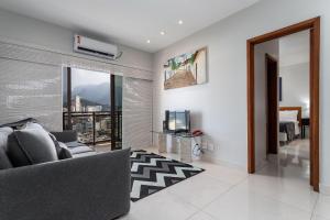 1 dormitorio y sala de estar con sofá y TV. en 180m PRAIA DO LEBLON, 2 Suítes, Vista Mar, ANDAR ALTO, Piscina etc en Río de Janeiro