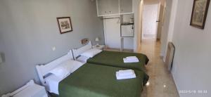 a room with two beds with green sheets at ODYSSEAS HOTEL SAMOS in Samos