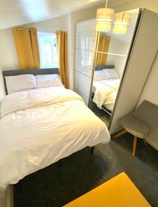 1 dormitorio con 1 cama blanca grande y espejo en Medway Getaway - 3 Bed Home with Luxury Bathroom en Chatham