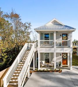 una casa blanca con una escalera que conduce a ella en Vacation Rental Bay St Louis walk to beach, dining, shopping, and nightlife en Bay Saint Louis