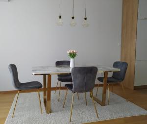 uma mesa de jantar com cadeiras e um vaso de flores em Apartman Lena em Banja Luka