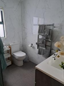 a white bathroom with a toilet and a sink at Sunbrae Beach Sanctuary free high Fibre wifi in Mount Maunganui