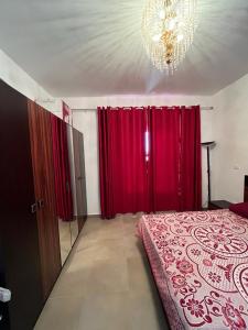 a bedroom with red curtains and a bed with a chandelier at amwaj in Dawwār Ruḩayyim