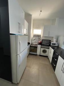 uma cozinha com armários brancos e um frigorífico preto em amwaj em Dawwār Ruḩayyim