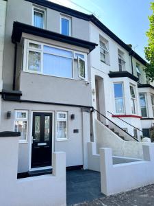 una casa blanca con una puerta negra y escaleras en The Wedge en Southend-on-Sea