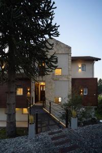 una casa con un árbol delante de ella en NBH Lacus Boutique Hotel en San Carlos de Bariloche