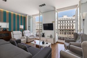 a living room with couches and a tv and large windows at BNBHolder Apartamentos en Sol Deluxe 2 in Madrid