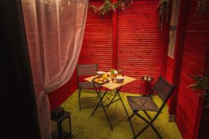 a small table and chairs in a room with a red wall at Le Carré Rose - Love Room proche de Rennes in Guichen