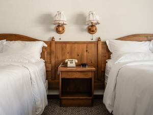 Habitación de hotel con 2 camas y mesa con teléfono en Enzian Inn, en Leavenworth