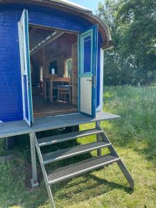 a blue out house with a staircase leading to it at Zirkuswagen im Weserbergland in Aerzen