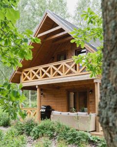 eine Blockhütte mit einer Veranda im Wald in der Unterkunft Siedlisko Modrej Czapli. Domki na Kaszubach in Klonowo Dolne
