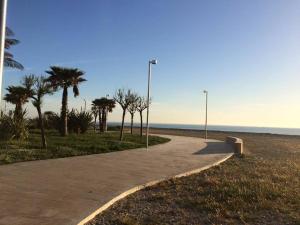 a walking path next to a beach with palm trees at B&B Indipendenza in Civitanova Marche