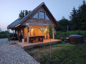 eine Hütte mit einer Holzterrasse mit einem Tisch und einer Badewanne in der Unterkunft Domek z bala na Podlasiu z balią ogrodową 