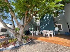 a patio with chairs and a tree in front of a building at Pousada Silvestre in Tramandaí