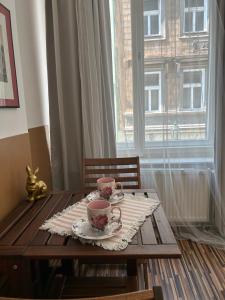 una mesa de madera con dos tazas y platillos. en Prague Old Town Apartment Benediktska 6, en Praga