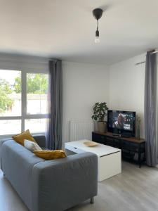 ein Wohnzimmer mit einem Sofa und einem TV in der Unterkunft Villejuif - Métro Léo Lagrange - 2 pièces avec balcon in Villejuif