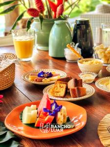 a wooden table topped with plates of cheese and bread at Pousada Rancho Luar in Pôrto de Pedras