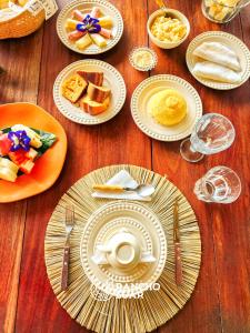 a wooden table with plates of breakfast food on it at Pousada Rancho Luar in Pôrto de Pedras