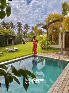 a woman standing in the water next to a swimming pool at Pousada Rancho Luar in Pôrto de Pedras