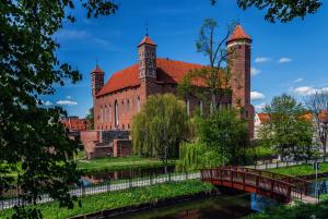 a large brick building with a bridge over a river at Apartament Alpaka 1 in Lidzbark Warmiński