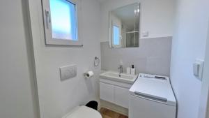 a white bathroom with a toilet and a sink at Cottage JANICE Beach in Pakoštane