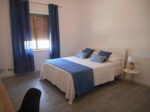 Un dormitorio con una cama con almohadas azules y una ventana en Nuli' - Delizioso Appartamento, en Trapani