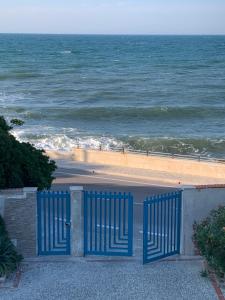 a blue gate in front of a beach with the ocean at Nontiscordardimé Apt in Torre a Mare