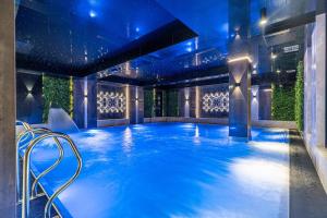 Białka TatrzanskaGóralski Resort Pool & SPA的建筑物内带有蓝色灯光的游泳池