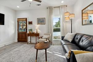 a living room with a leather couch and a table at Cozy Vacation Rental in Old Town Bay St Louis close to beach, bars, and dining in Bay Saint Louis