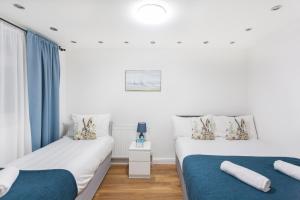 two beds in a room with blue curtains at Holloway Budget Apartment - 1 Minute to Emirates Stadium - Next to Station - City Center in London