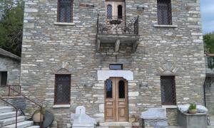 ein großes Steingebäude mit einer Holztür und einer Treppe in der Unterkunft Anovolios Boutique Hotel in Agios Georgios Nileias