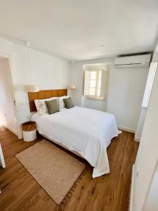 een witte slaapkamer met een groot bed en een raam bij The Bird House in Nazaré