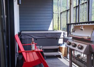 a patio with a red chair and a grill at Stoke House by Revelstoke Vacations in Revelstoke