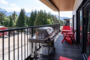 a balcony with a grill and wine glasses on it at Stoke House by Revelstoke Vacations in Revelstoke