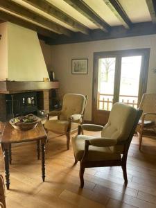 a living room with chairs and a table and a fireplace at Maison familiale in Saint-Pierre-dels-Forcats