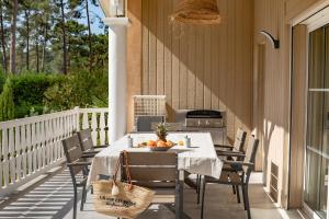 porche con mesa, sillas y fogones en Belle villa familiale rénovée dans cadre exceptionnel-AG15, en Lacanau