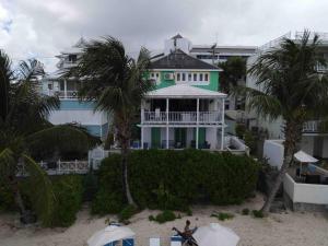a green and white house on the beach with palm trees at Charleston Beach House Barbados in Bridgetown