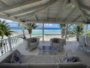 布里奇敦的住宿－Charleston Beach House Barbados，一个带沙发和椅子的门廊和海滩