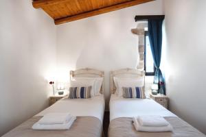 two beds in a room with white walls at Villa Eliomylos in Souda