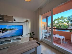 een woonkamer met een grote televisie en een balkon bij Tropical chic in Casares