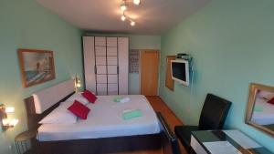 a small bedroom with a white bed with red pillows at House Lanterna Pag in Pag