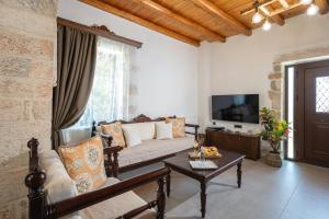 a living room with a couch and a tv at Villa Eliomylos in Souda
