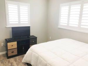a bedroom with a bed and a dresser and two windows at Modern Apartment - 1 of 4 in Punta Gorda