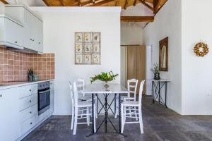 a kitchen with white cabinets and a table and chairs at Althea in Panormos Skopelos